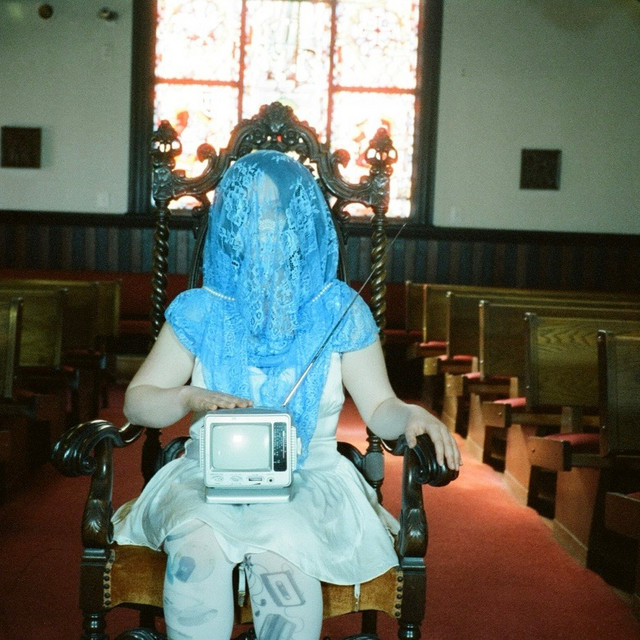 Penelope Scott siting down at a church holding an old TV